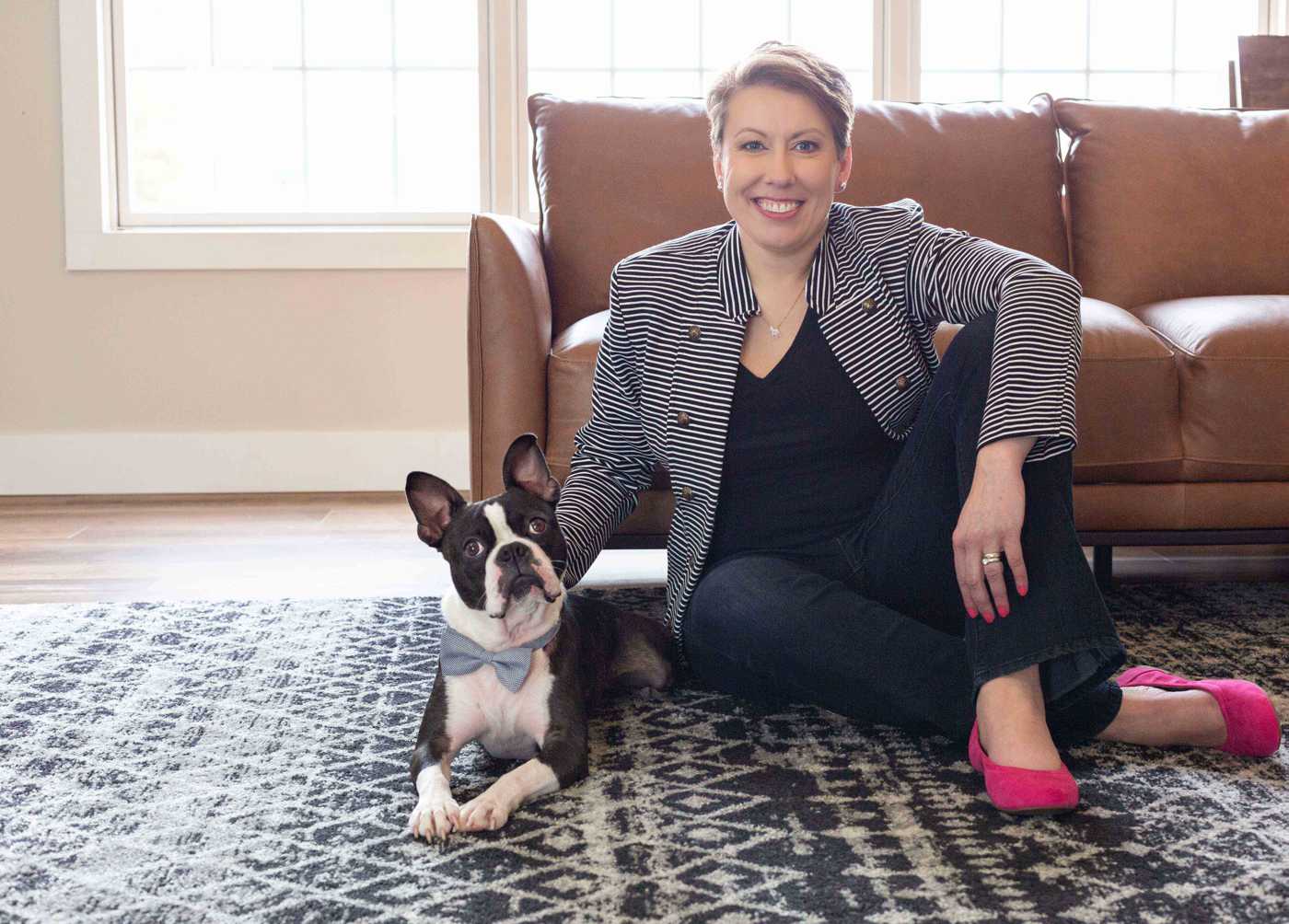 woman poses with dog in front of a couch