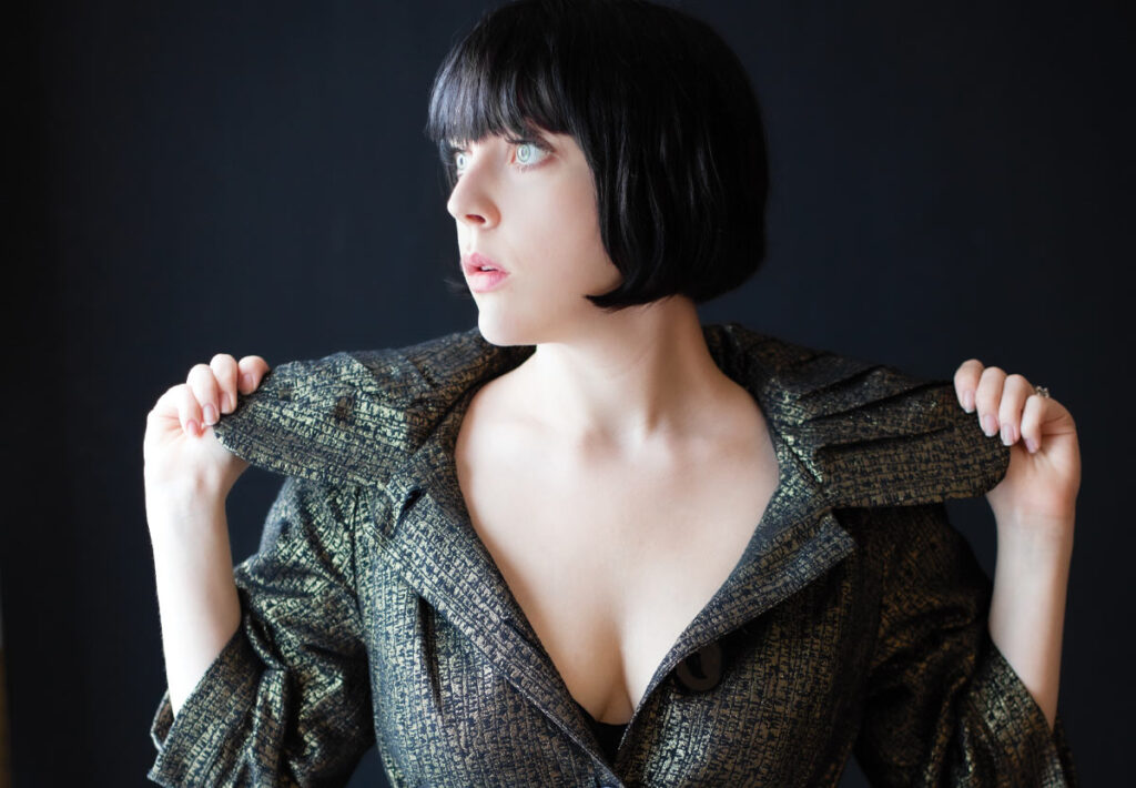 Woman with short black hair poses for portrait in a stylish coat