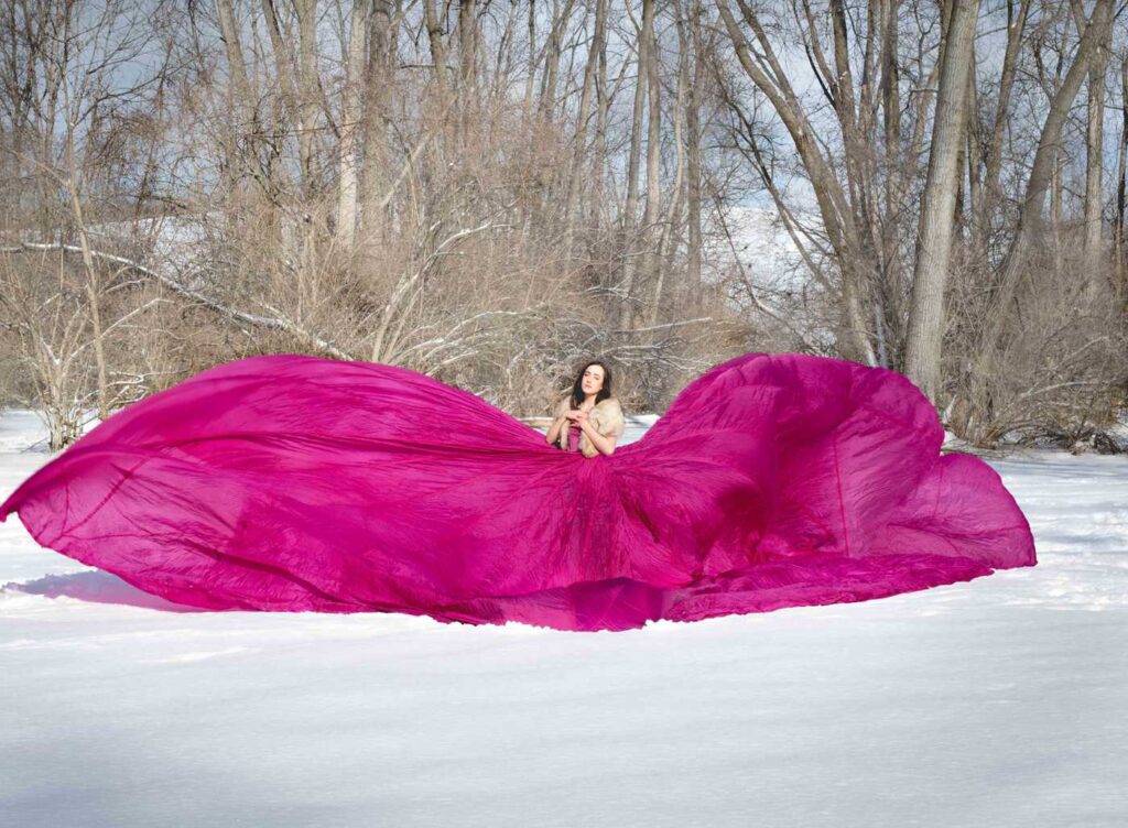 teen poses in a parachute dress in the snow